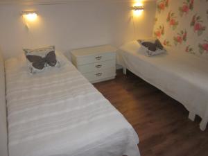 2 camas en una habitación pequeña con sábanas blancas en Huldas Gård, en Kumla