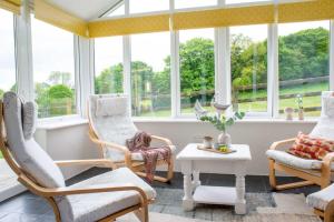 Habitación con sillas, mesa y ventanas. en Bosinver Farm Cottages Buddleia en St Austell