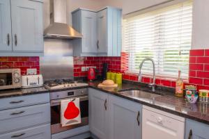 cocina con fregadero y fogones horno superior en Bosinver Farm Cottages Buddleia en St Austell