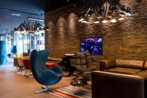 a lobby with couches and chairs and a brick wall at Motel One Wien-Prater in Vienna