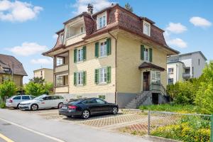 a house with cars parked in front of it at Erlen Rooms in Lucerne