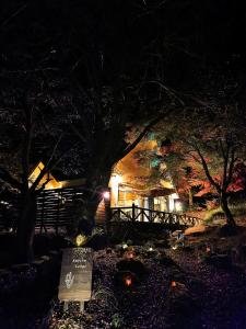 una casa por la noche con un cartel delante en 星空に包まれる 森の隠れ家　Amrita Lodge ~stay & retreat~ en Kirishima