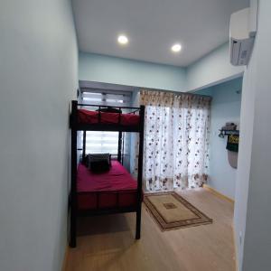 Habitación pequeña con 2 literas y sábanas rojas. en HOMESTAY WEE INN JB en Johor Bahru