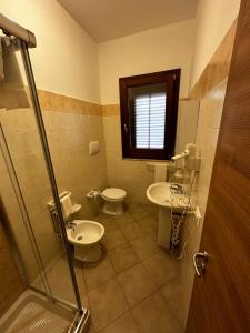a bathroom with two sinks and a toilet and a shower at Samira in San Vito lo Capo
