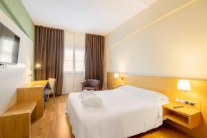 ein Hotelzimmer mit einem weißen Bett und einem Schreibtisch in der Unterkunft IBERIK Augas Santas Balneario & Golf in Pantón
