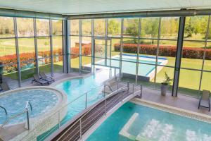 uma piscina interior num edifício com paredes de vidro em IBERIK Augas Santas Balneario & Golf em Pantón