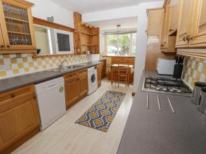 a kitchen with wooden cabinets and a stove top oven at Little Rosemount in Tenby