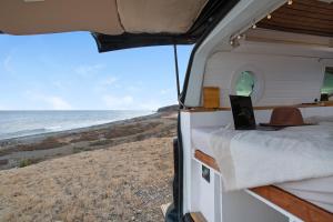 Una caravana con un ordenador portátil en la playa en Inikcamper en Ingenio