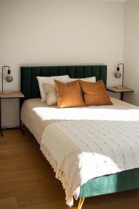 a bed with a green headboard and some pillows at Apartment in Kesterciems in Ķesterciems