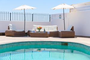 una piscina con sillas y sombrillas en un patio en Villa Linda, en Playa Blanca