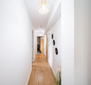a hallway with white walls and a wooden floor and a chandelier at Bv Charming Studio with Free Private Parking, 10 Minutes from Town Centre in Leeds