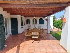une terrasse avec une pergola en bois, une table et des chaises dans l'établissement Villa Xalina - Piscina / bbq / jardín, à Fornells