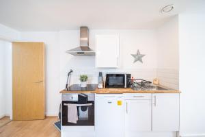 uma pequena cozinha com armários brancos e um micro-ondas em Bv Charming Studio with Free Private Parking, 10 Minutes from Town Centre em Leeds