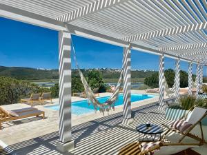 a patio with a hammock and a swimming pool at Herdade D’ Amoreira Aljezur in Aljezur