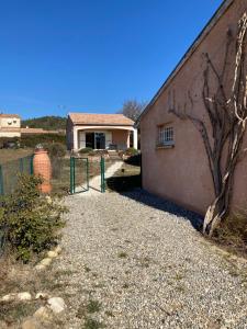 a house with a gravel driveway next to a building at La paisible du Verdon in Vinon-sur-Verdon