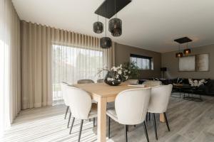 een eetkamer met een houten tafel en witte stoelen bij Amazing holiday home "Beaunita" with 4 bedrooms and 4 bathrooms in Hamont