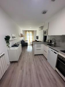a kitchen with white cabinets and a living room at Apartamento Entre Ríos in Tudela