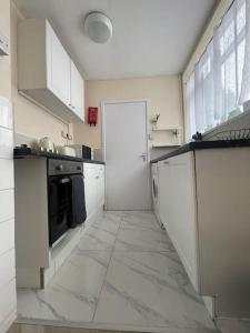 a kitchen with white cabinets and a large tile floor at Stunning 1 Bedroom Home in Southend-on-Sea