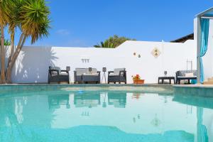 una piscina con mesa y sillas junto a una pared blanca en Villa Linda, en Playa Blanca