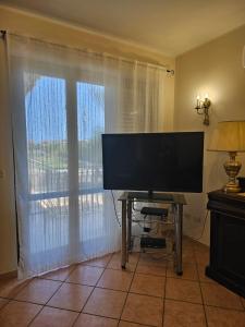 a flat screen tv in a living room with a window at ORITAN HOUSE in Schisò