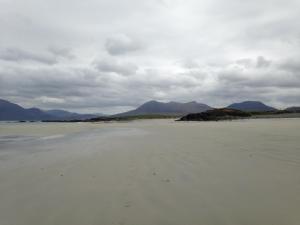 an empty beach with mountains in the background at Oranmore Apartment on the Wild Atlantic Way in Oranmore