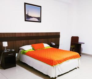 Manta Airport Hotel في مانتا: غرفة نوم مع سرير مع لحاف برتقالي