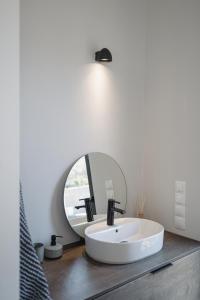 a bathroom with a white sink and a mirror at NIMA Suites in Paleros
