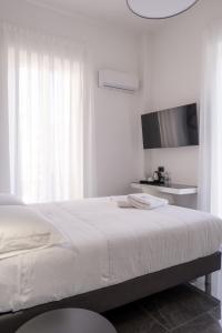 a white bedroom with a bed and a tv at Domea Superior Rooms Bed and Breakfast in Reggio Calabria