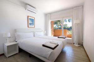 Un dormitorio con una gran cama blanca y una ventana en Villa Familiar by La Costa Resort, en Pals