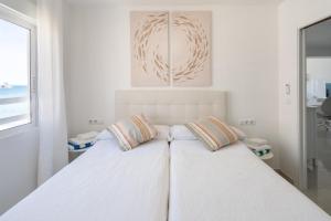 a white bedroom with a bed with two pillows at El Acuario - Primera línea y todas las ventanas dan al mar in Cullera