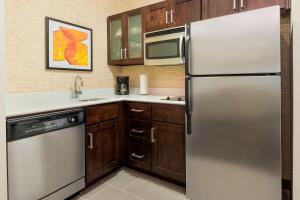 a kitchen with a stainless steel refrigerator and wooden cabinets at Residence Inn Savannah Midtown in Savannah