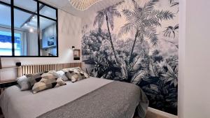 sypialnia z łóżkiem z malowidłem palmowym w obiekcie En plein centre de cannes à 2 pas de la croisette w Cannes
