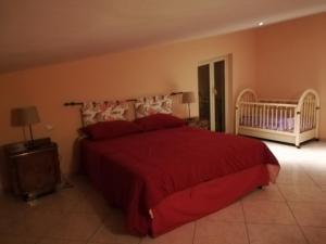 a bedroom with a red bed and a crib at Casa Carmelo in Nizza di Sicilia