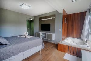 een slaapkamer met een bed, een bad en een televisie bij Casasparaisomorro - Apartamento com hidromassagem in Morro de São Paulo