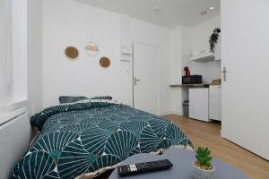 um quarto com uma cama e um controlo remoto em Charmant Studio à 10 min de la gare em Saint-Quentin