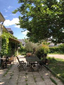 un patio con mesa y sillas bajo un árbol en LA FERME DE RUSSÉ en Allonnes