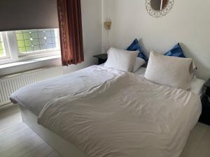 un letto con lenzuola e cuscini bianchi in una camera da letto di Historische gelegen appartement more Days a Dedemsvaart