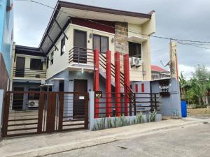 uma casa com uma cerca vermelha em frente em Cozy Space Near SM with Netflix and Fiber WiFi em Batangas City