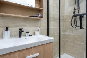 uma casa de banho com um lavatório branco e um chuveiro em La Perle de Laigneville - Proche Parc Astérix & Chantilly, parking public gratuit, Wifi & Netflix 