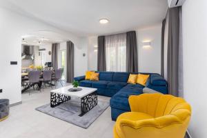 uma sala de estar com um sofá azul e cadeiras amarelas em Villa Romano by IstriaLux em Benažići