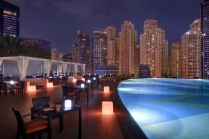 a swimming pool with tables and chairs and a city skyline at Spacious, Modern Studio in Marina Dubai in Dubai