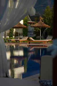 Palmonte Suites Hotel & SPA في كيرينيا: مسبح مع كراسي الصالة والمظلات بجانب الماء