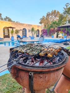 a grill sitting in front of a pool at Riad Eucalyptus by Caravanserail in Essaouira
