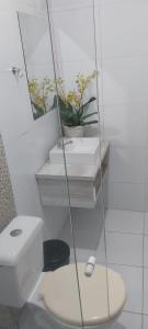 a white bathroom with a toilet and a mirror at Pousada Colina do Sol in Ametista do Sul