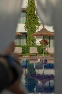 un reflejo de dos sillas y una sombrilla en una piscina en Palmonte Suites Hotel & SPA en Kyrenia