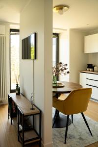 a dining room and kitchen with a table and a yellow chair at Apartment in Kesterciems in Ķesterciems