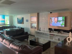a living room with couches and a flat screen tv at Loft da Prainha in Arraial do Cabo