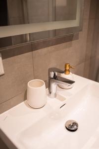 ein weißes Waschbecken mit einer Tasse und einem Wasserhahn im Bad in der Unterkunft Apartment in Kesterciems in Ķesterciems