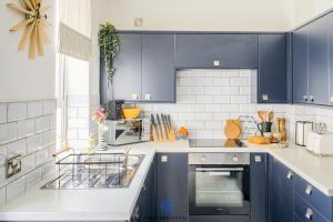 eine Küche mit blauen Schränken und einer Spüle in der Unterkunft Doncaster Large Luxury 3 Bedroom House, Sleeps 8, City Centre, Racecourse, Free Parking, by EMPOWER HOMES in Doncaster + 17 Fotos