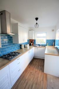 a kitchen with white cabinets and blue tiles on the wall at Contemporary Home in Friendly Easton, Free Parking in Bristol